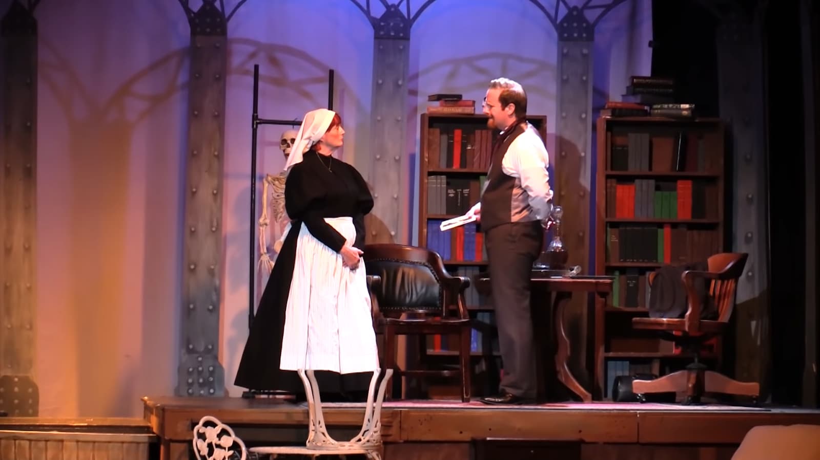A staged scene with a woman in maid attire and a man with papers