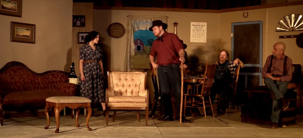 A staged scene from "The Rainmaker" with four actors in period costumes