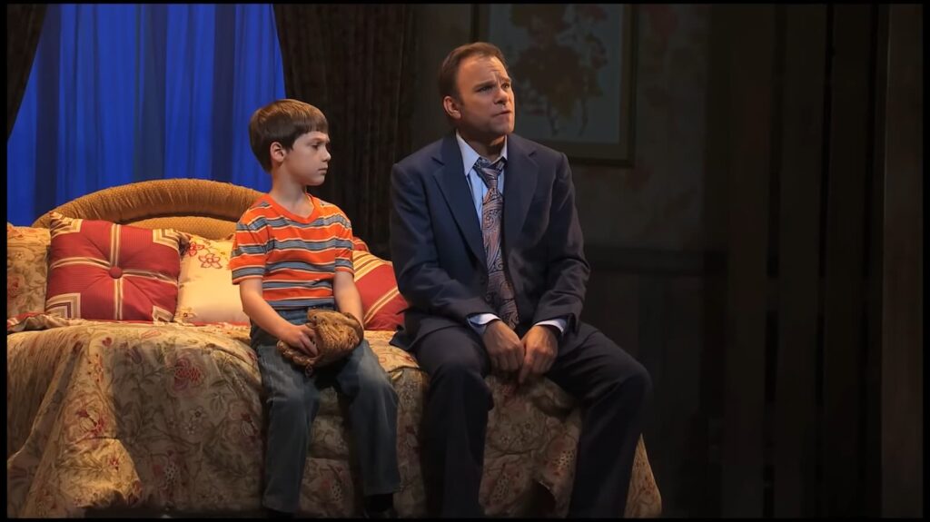 A man in a suit and a boy on a bed look intently to the side